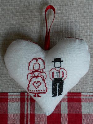 Un coeur en lin sur lequel est brodé un couple alsacien. Le femme porte une robe ornée d'un coeur.